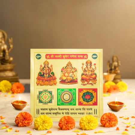 Shree Lakshmi Kubera Ganesh Yantra with marigold flowers and oil lamps on white surface