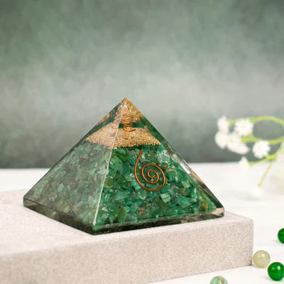 Green jade crystal pyramid orgonite with copper spiral on beige surface, blurred background