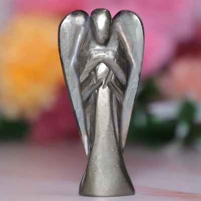 Metal angel figurine with outstretched wings and abstract design on blurred colorful background