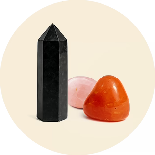 Black crystal tower and two polished stones, pink and orange, on a light background