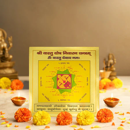 Yellow Vastu Dosha Nivaran Yantra with orange and yellow marigold flowers and lit clay oil lamps